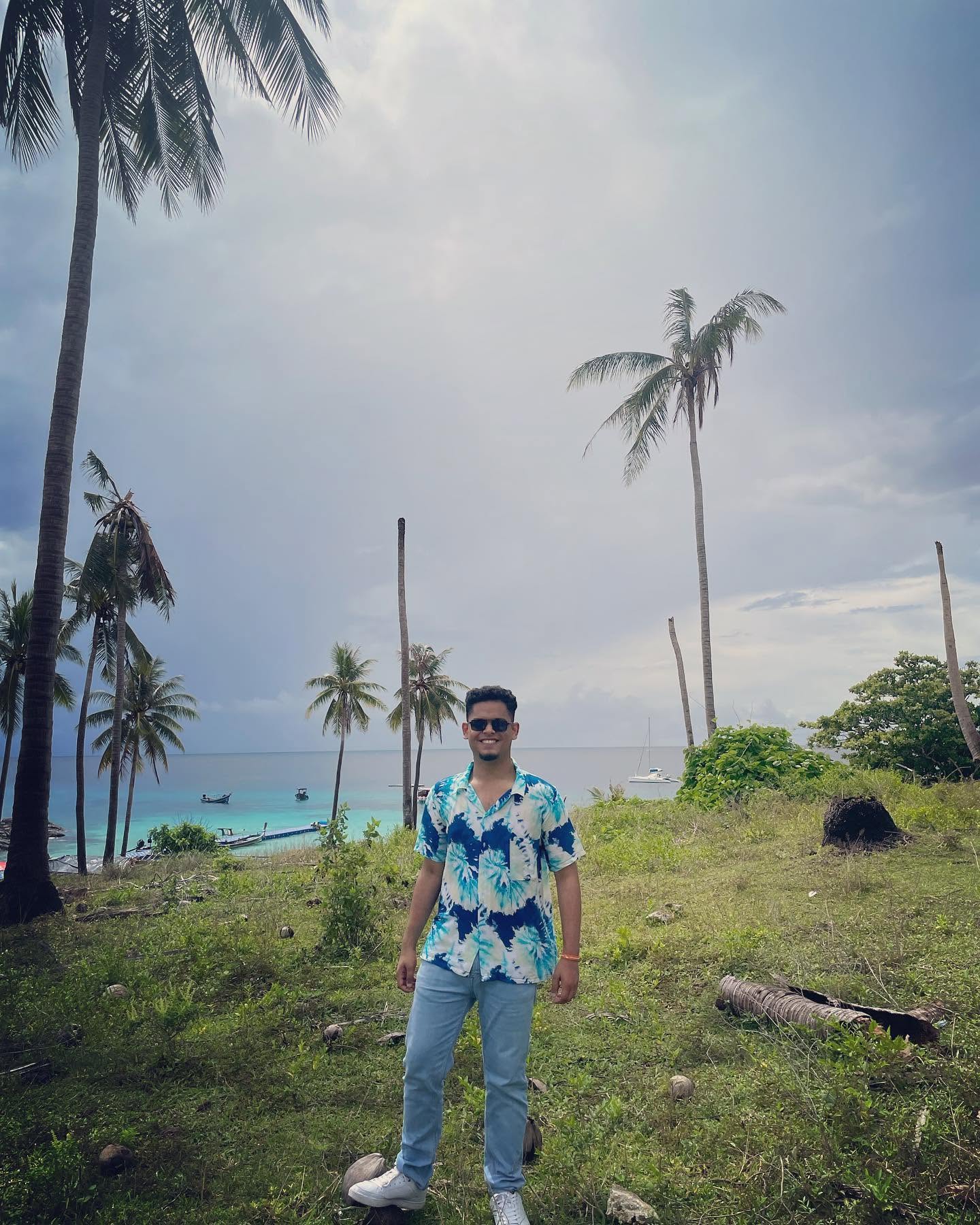 Rifat standing by the sea beneath palm trees